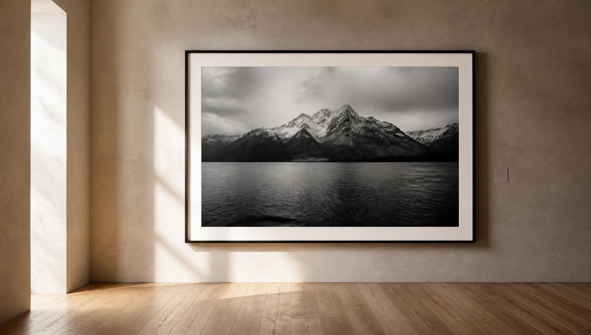 A large framed black and white landscape print on a warm plaster gallery wall